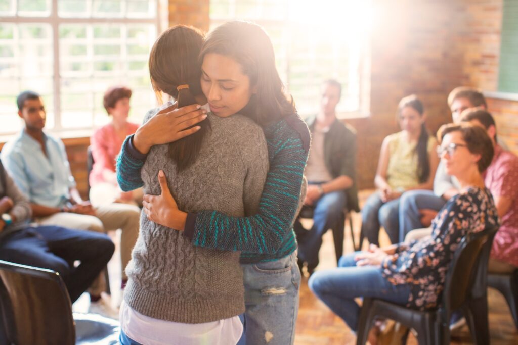 Home 4 Two women hugging at group Christian therapy in Austin.