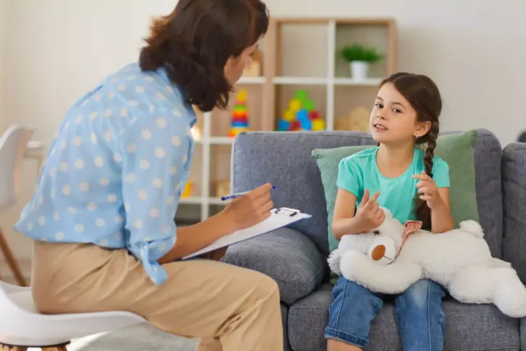 Eight-year old girl talks to her Austin therapist while holding a stuffed animal.
