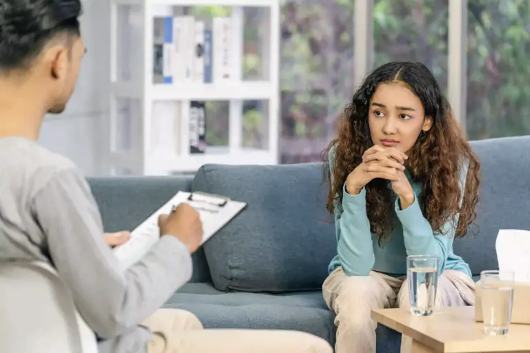 Teenage girl rests her head on her hands while talking to a therapist in Austin.