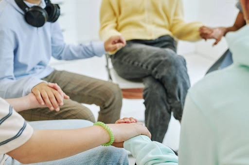 Group of teens holding hands during IOP group therapy session.
