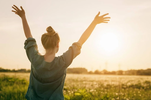 Woman putting arms in air to express peace and joy.