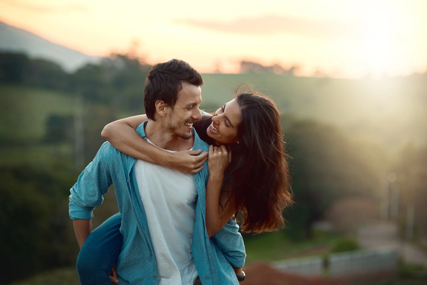 Woman and man embracing at sunset in outdoor space.