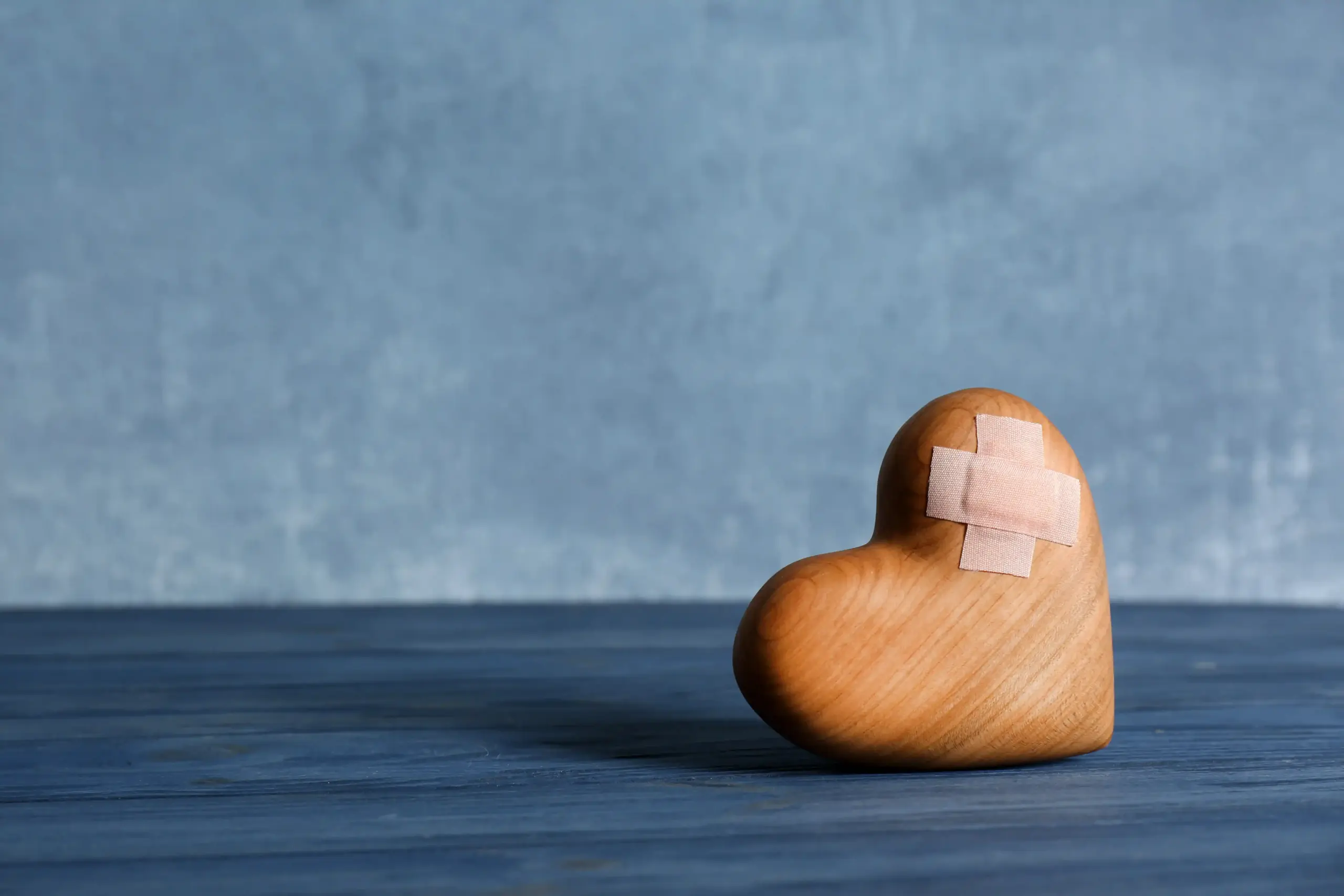 Wooden heart with band aids symbolizing healing after loss.