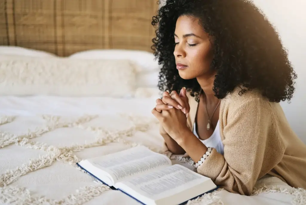 Faith-Based Therapy Benefits for Moral Injury and Faith Crisis 1 A woman praying beside an open Bible, finding peace through faith and Christian therapy.