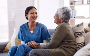 Caregiver in scrubs sharing a warm moment with an aging parent, a role at high risk for burnout