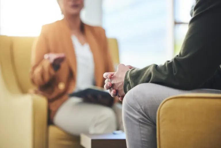 Man with clasped hands listening to his therapist during an anxiety therapy session in Austin
