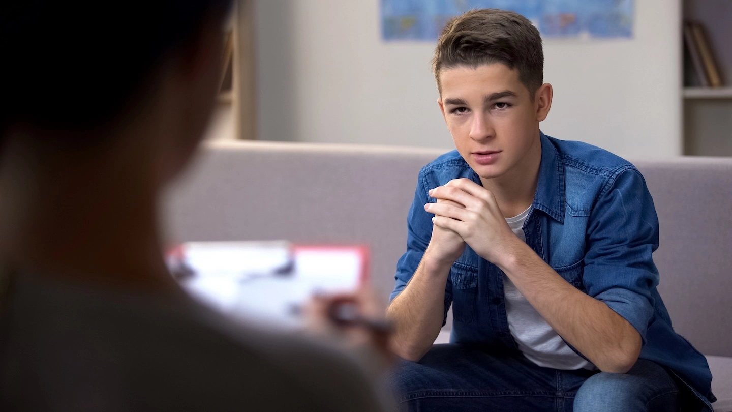 Teen boy talking with his counselor during a therapy session 
