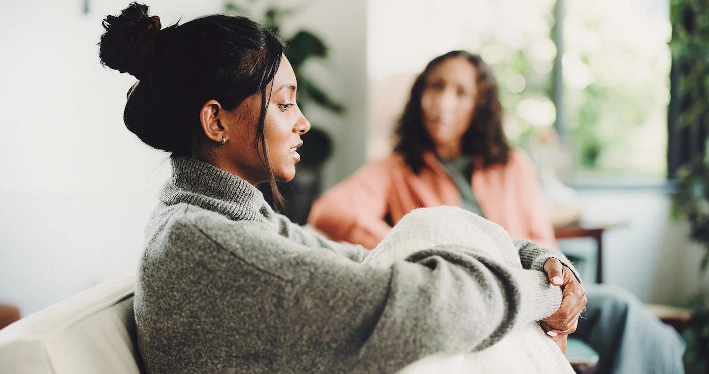 Woman sitting in a therapy session, listening thoughtfully as her therapist talks with her in Austin.